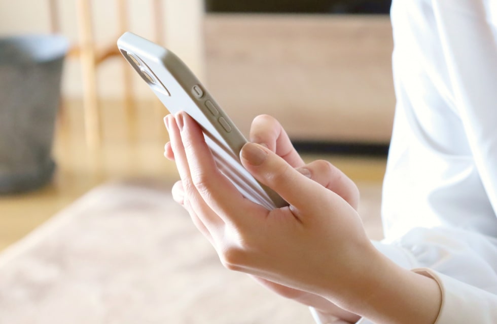 スマホで問い合わせする女性の手